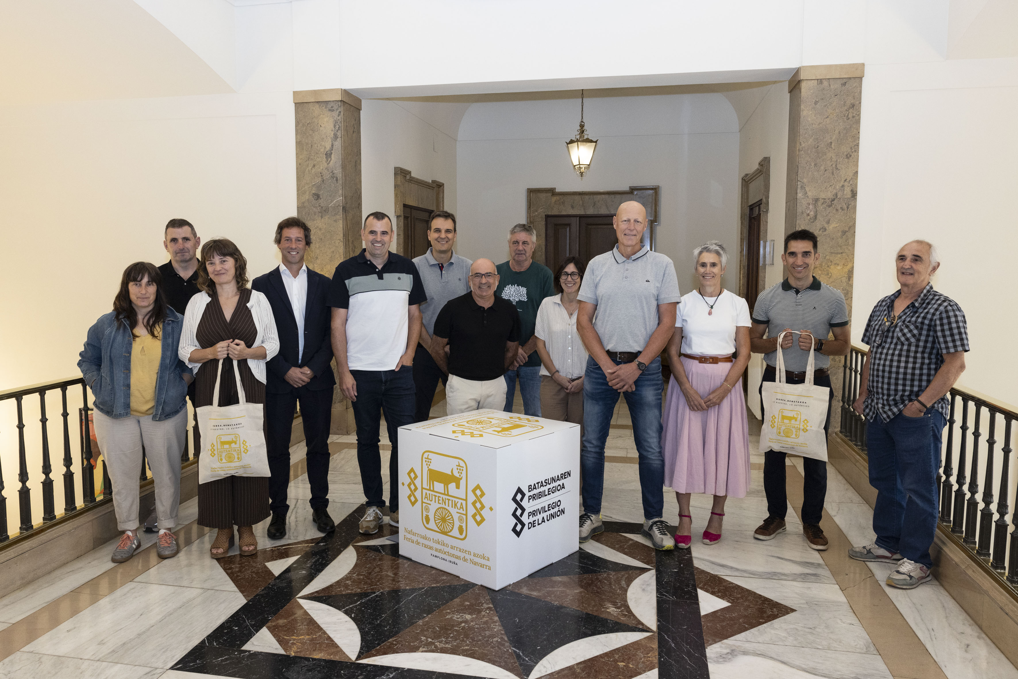 Foto de un grupo de personas detrás de un cubo con el logo de la feria y dos de ellos sosteniendo bolsas de la misma