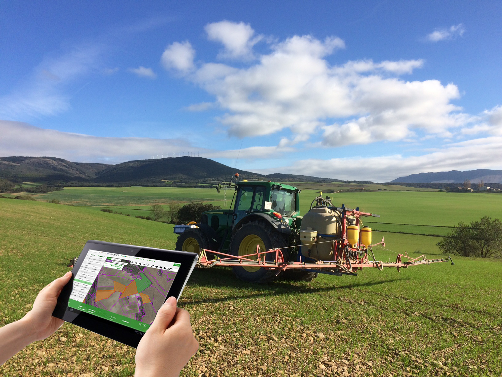 Fotografía de un tractor en el campo y una mano sosteniendo una tablet