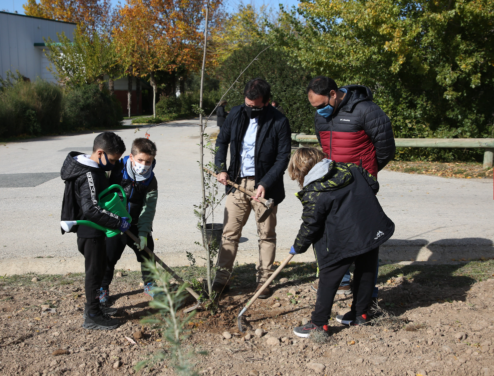 Fotografía de Mikel Irujo junto a otro hombre y 3 niños plantando un arbol