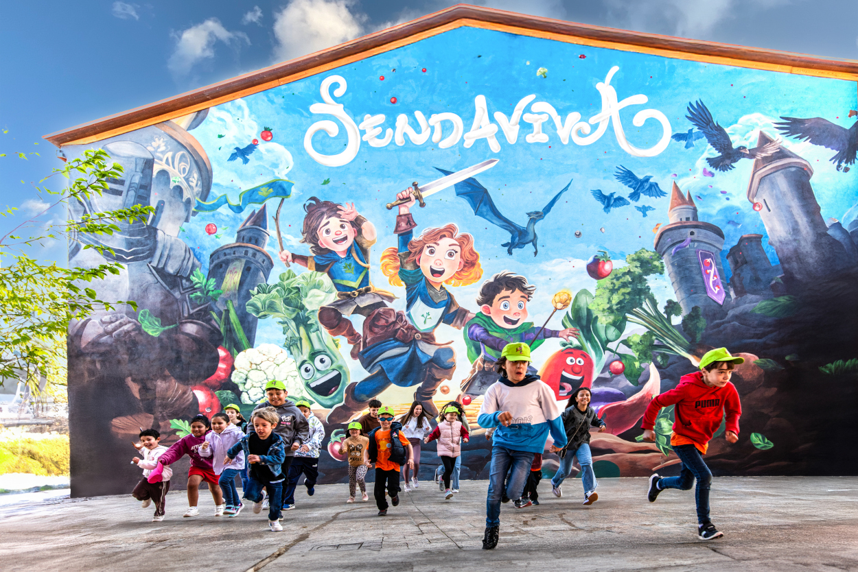 Niños corriendo delante de un mural de Sendaviva