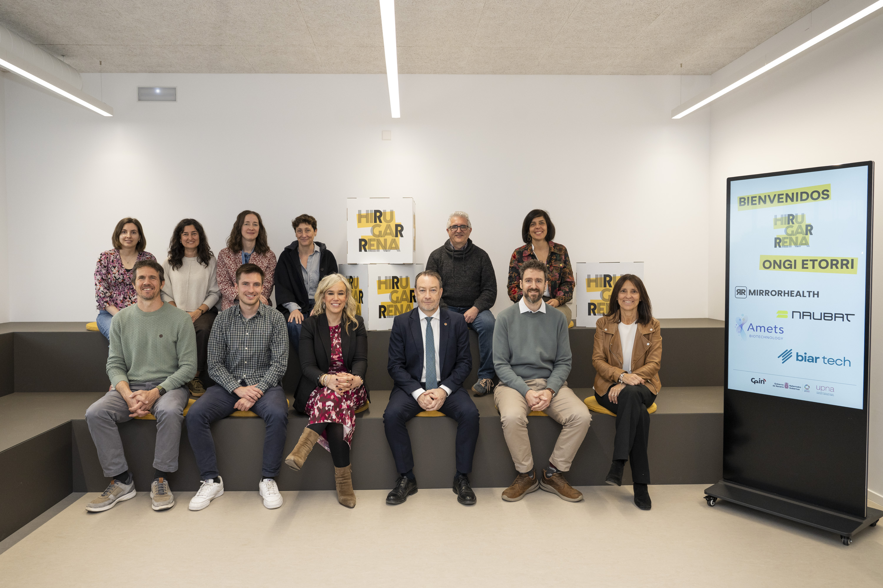 Grupo de personas posando en dos filas con cubos con el logo del espacio HIRUGARRENA