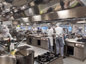 Fotografía de una cocina industrial y varios cocineros cocinando