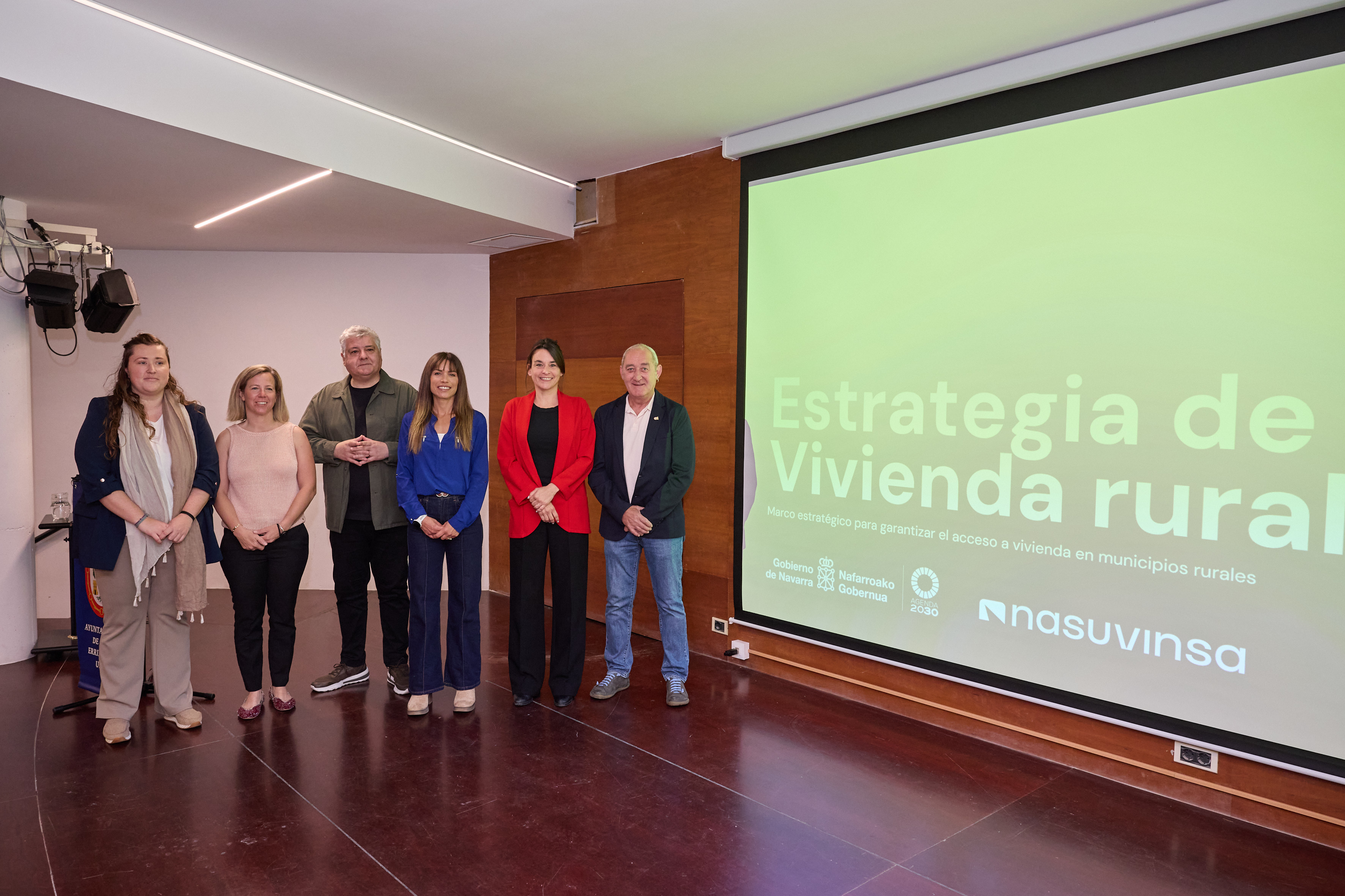 6 personas posando delante de una pantalla