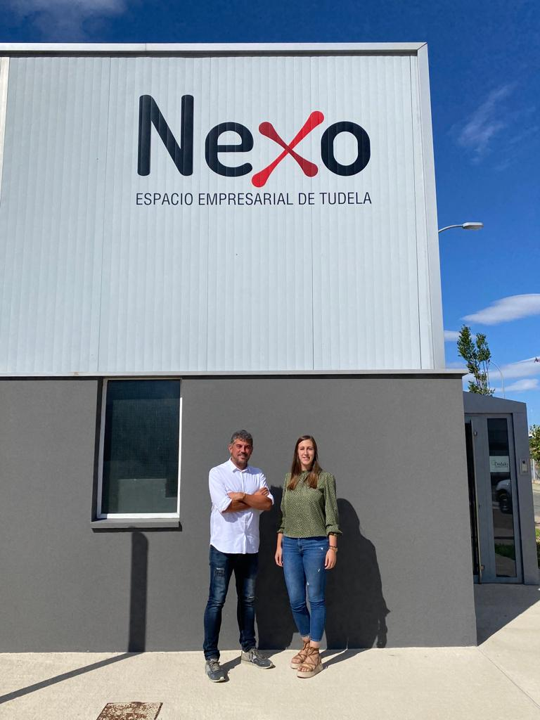 Fotografía de dos personas delante de la fábrica Nexo