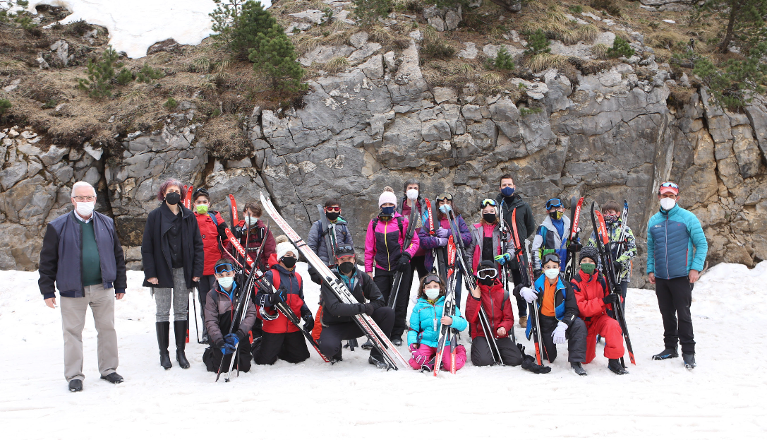 Fotografía en la nieve donde salen cinco adultos y dieciséis niños y niñas con esquís.