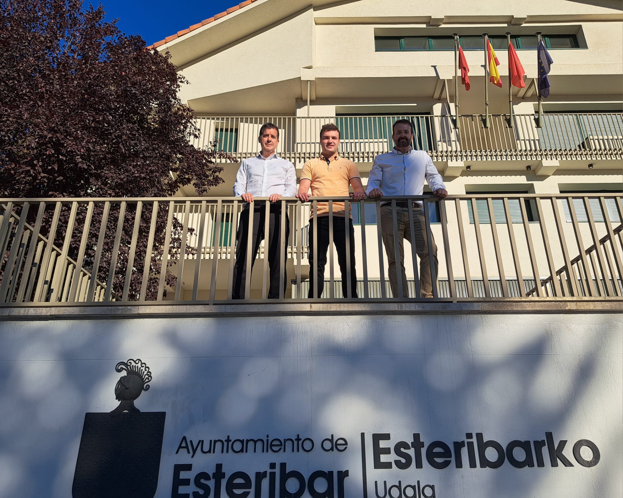 3 personas posando desde lo alto de un balcón