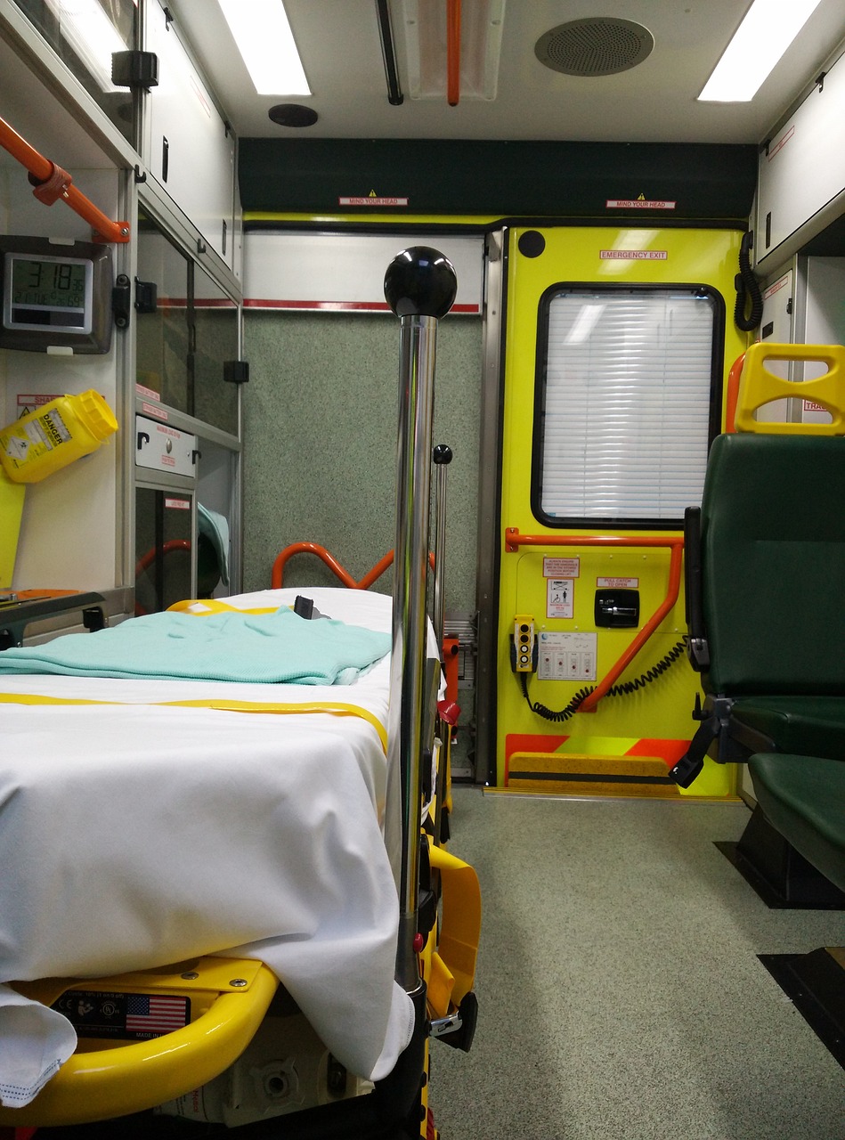 Fotografía del interior de una ambulancia. A mano izquierda se ve una camilla y de fondo una puerta amarilla.