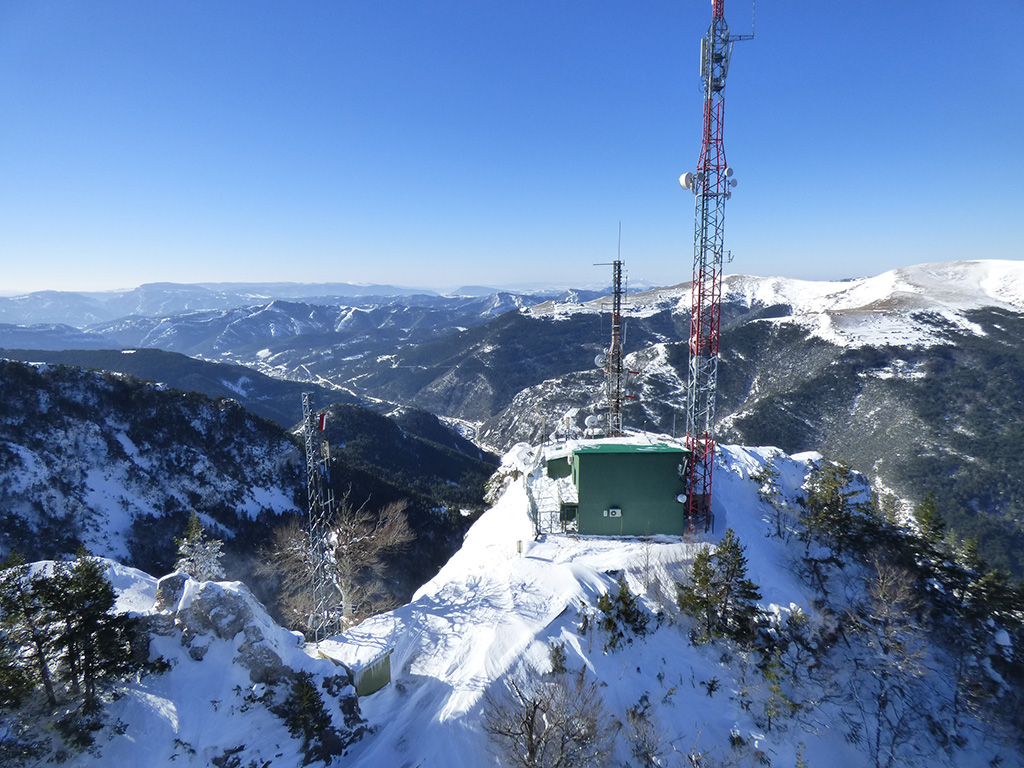Fotografía de montes nevados con una torre eléctrica en la cima de uno de ellos