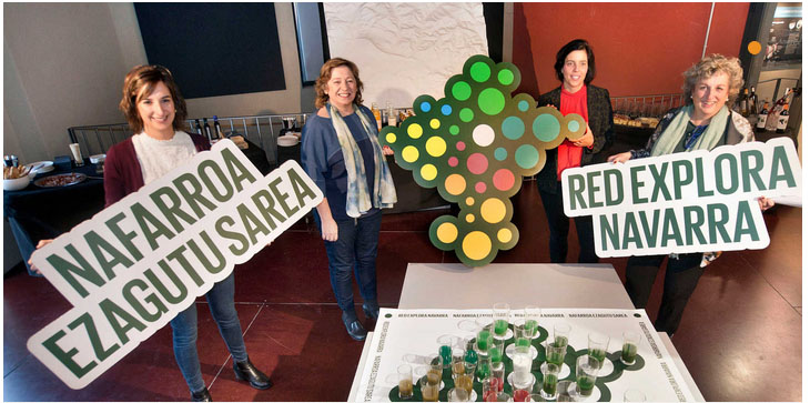 Micaela García, la consejera Isabel Elizalde, Uxue Itoiz y Arantxa Arregui, durante la presentación de la Red Explora Navarra, sobre un mapa formado por zumos elaborados con productos locales de cada comarca.