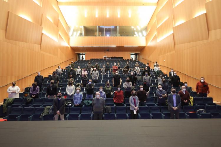 Fotografía de una sala con butacas y con personas que están de pie. 