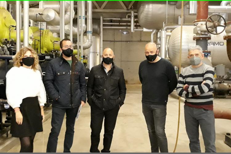 Fotografía de cuatro hombres y una mujer dentro de una nave industrial. 
