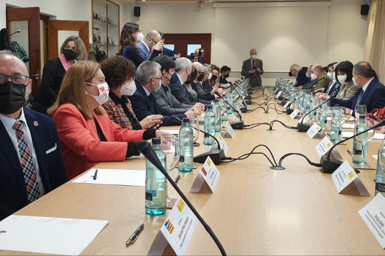 Fotografía de una mesa alargada de reuniones, con personas sentadas a ambos lados y, en primer término, a mano izquierda se observa al consejero Cigudosa