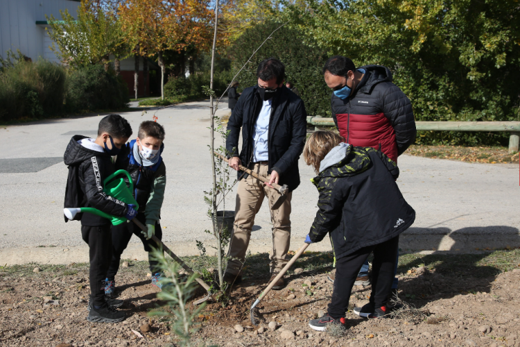 Fotografía de Mikel Irujo junto a otro hombre y 3 niños plantando un arbol