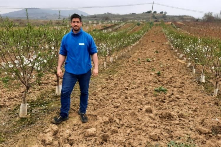 Carlos Marzo, a la izquierda de la imagen con ropa de trabajo de color azul, con la finca experimental de Cadreita como fondo