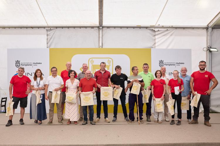 Varias personas posando con bolsas de tela con el logotipo de la feria